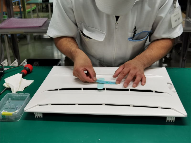 アンデス電気　空気清浄機バイオミクロンBM-H101A　製造工場レポートページ　フロントカバーへロゴシール貼り付けの様子